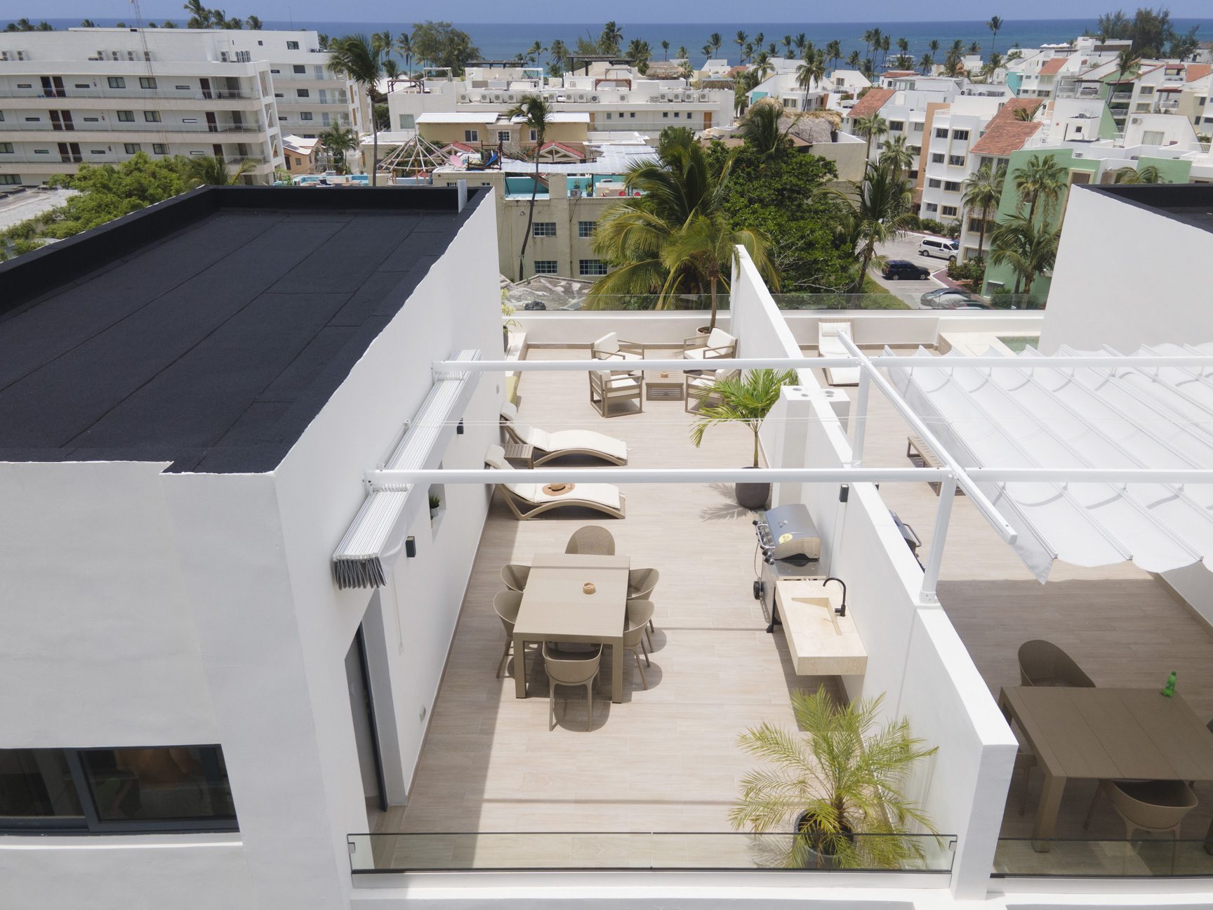 buyDRproperty Rooftop terrace with modern outdoor furniture, dining area, lounge chairs, and ocean view. Sosua Real Estate