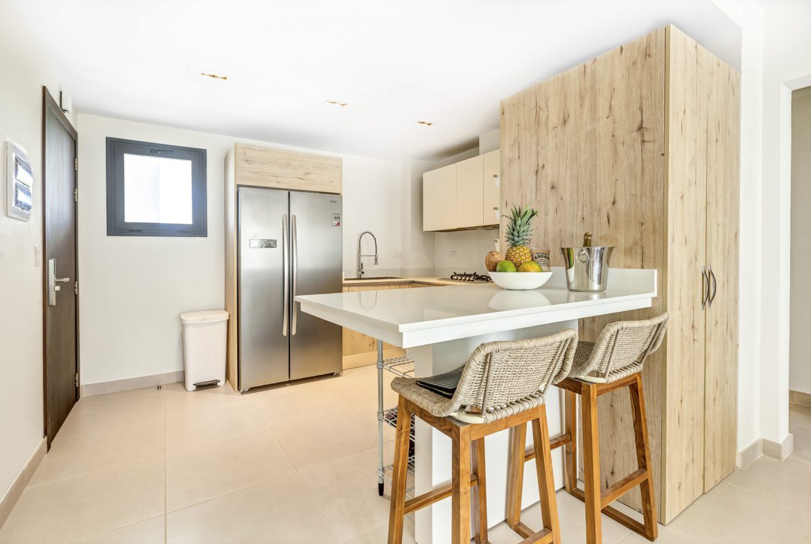 buyDRproperty Modern kitchen with island, stainless steel fridge, and wicker bar stools Sosua Real Estate