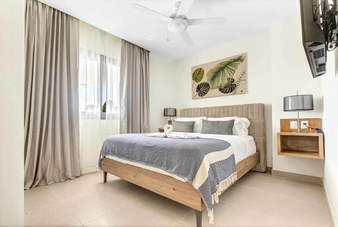 buyDRproperty Bedroom with queen bed, tropical art, and neutral decor. Sosua Real Estate