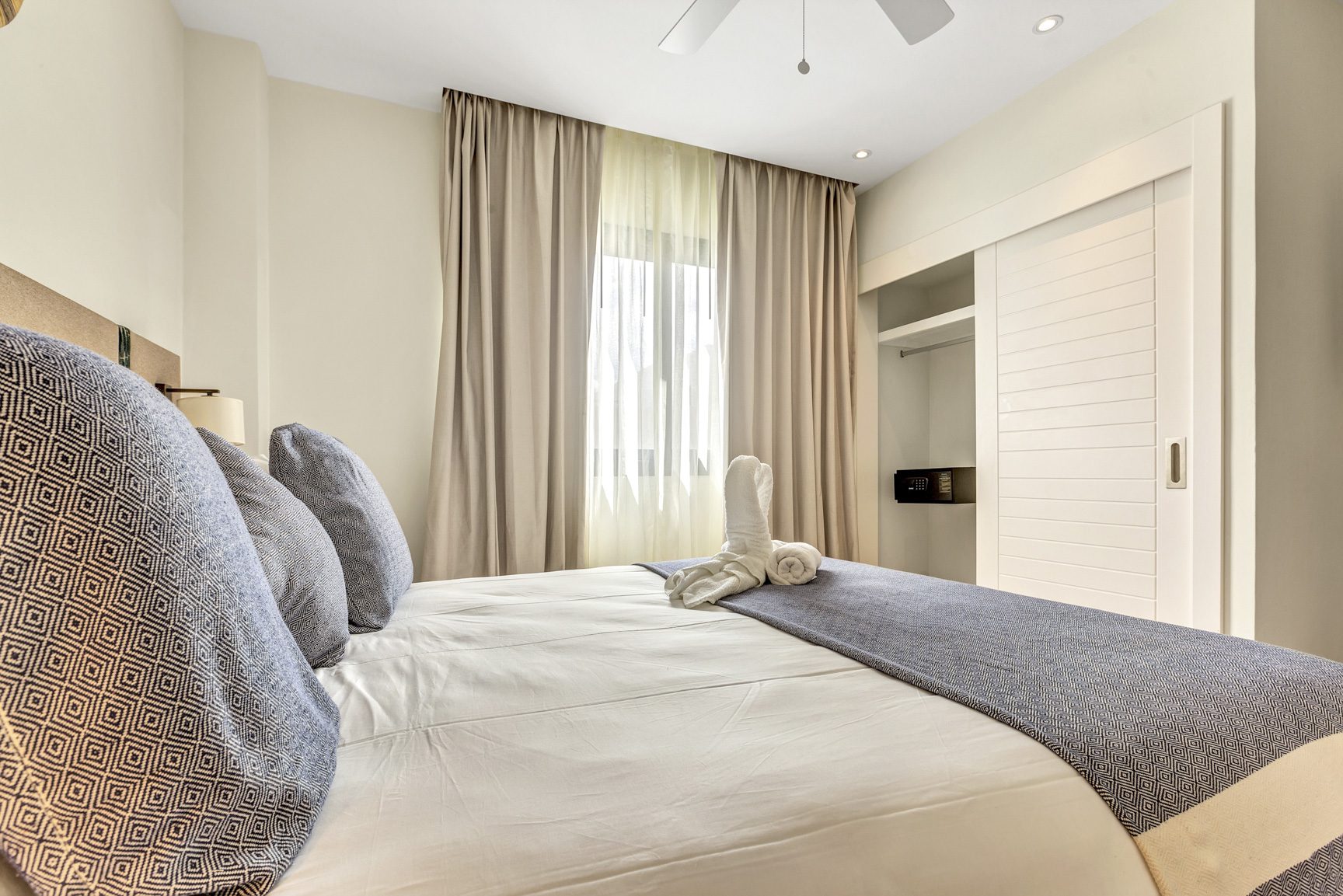 buyDRproperty Bright bedroom with white linens, blue accents, and a closet with sliding doors. Sosua Real Estate