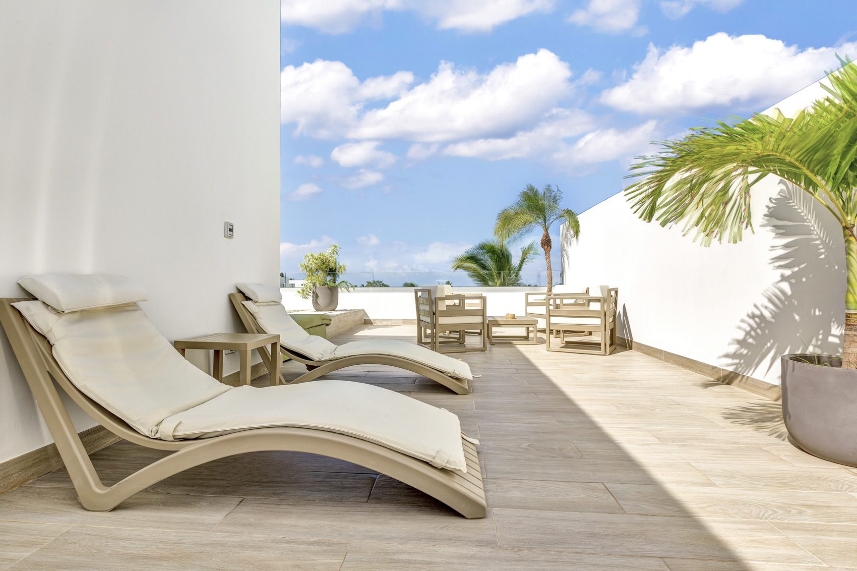 buyDRproperty Luxury patio with lounge chairs, outdoor seating, and palm tree against a sunny sky. Sosua Real Estate