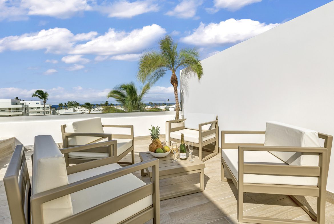 buyDRproperty Luxury rooftop terrace with seating, champagne, and tropical fruit. Sosua Real Estate