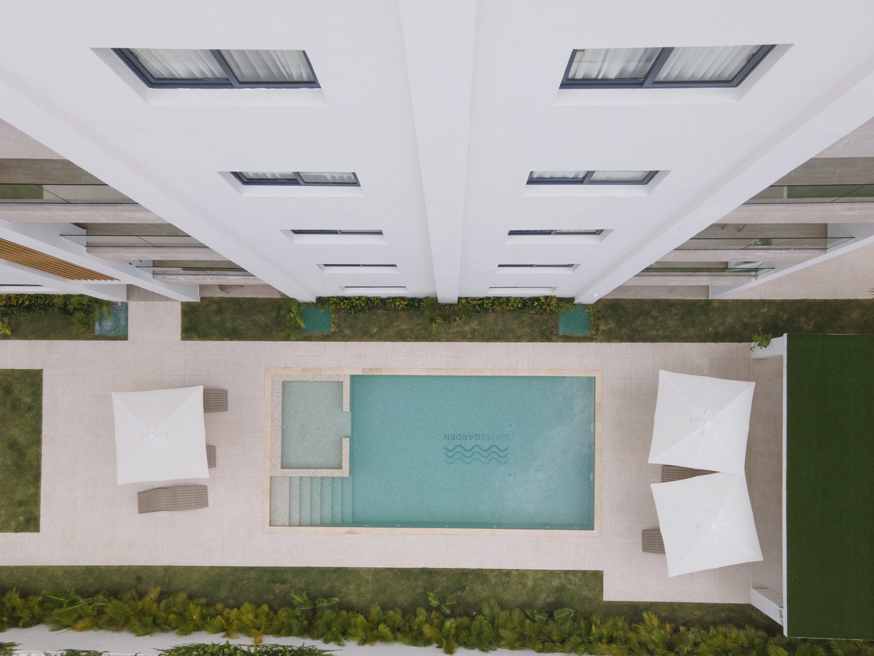 buyDRproperty Overhead view of a modern building with a pool, lounge chairs, and umbrellas. Sosua Real Estate