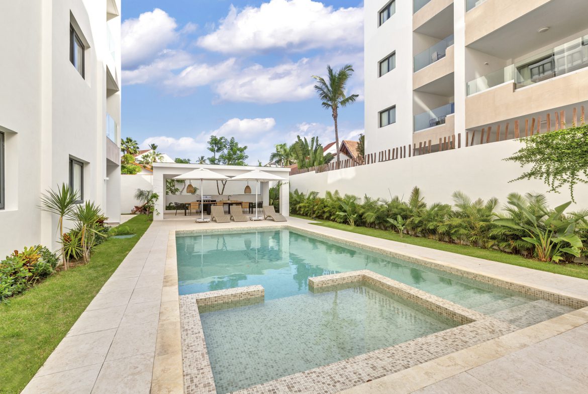 buyDRproperty Luxury condo pool with lounge chairs and tropical landscaping. Sosua Real Estate