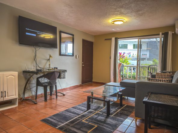 buyDRproperty Cozy living room with TV displaying a Netflix error message, glass coffee table, and outdoor view. Sosua Real Estate
