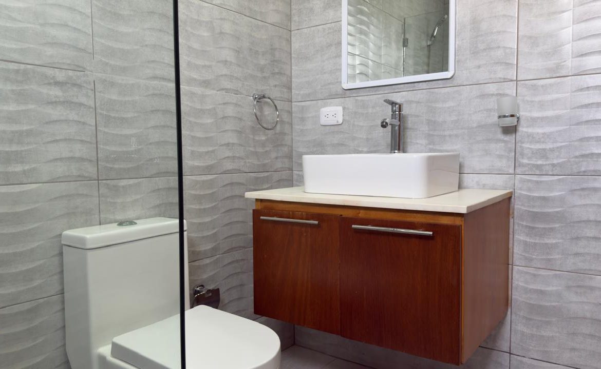Modern bathroom with gray wave tile, floating wood vanity, and white square sink.