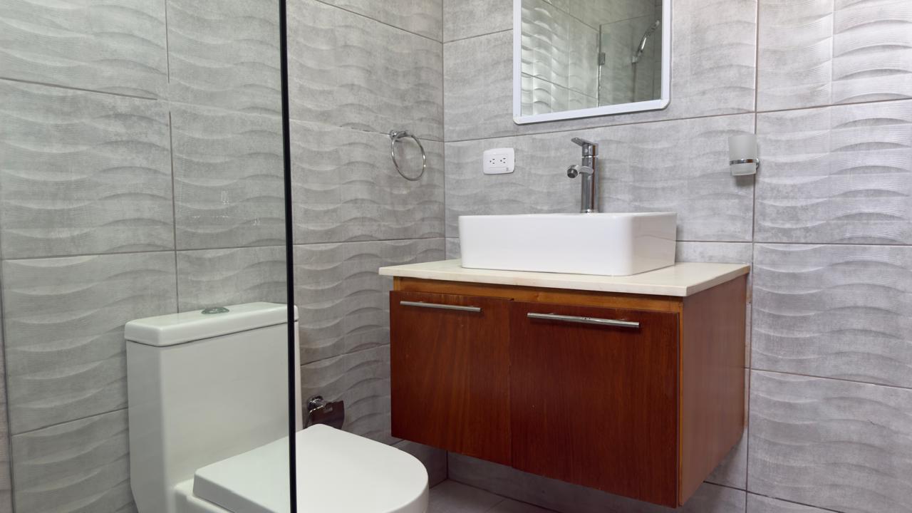 Modern bathroom with gray wave tile, floating wood vanity, and white square sink.