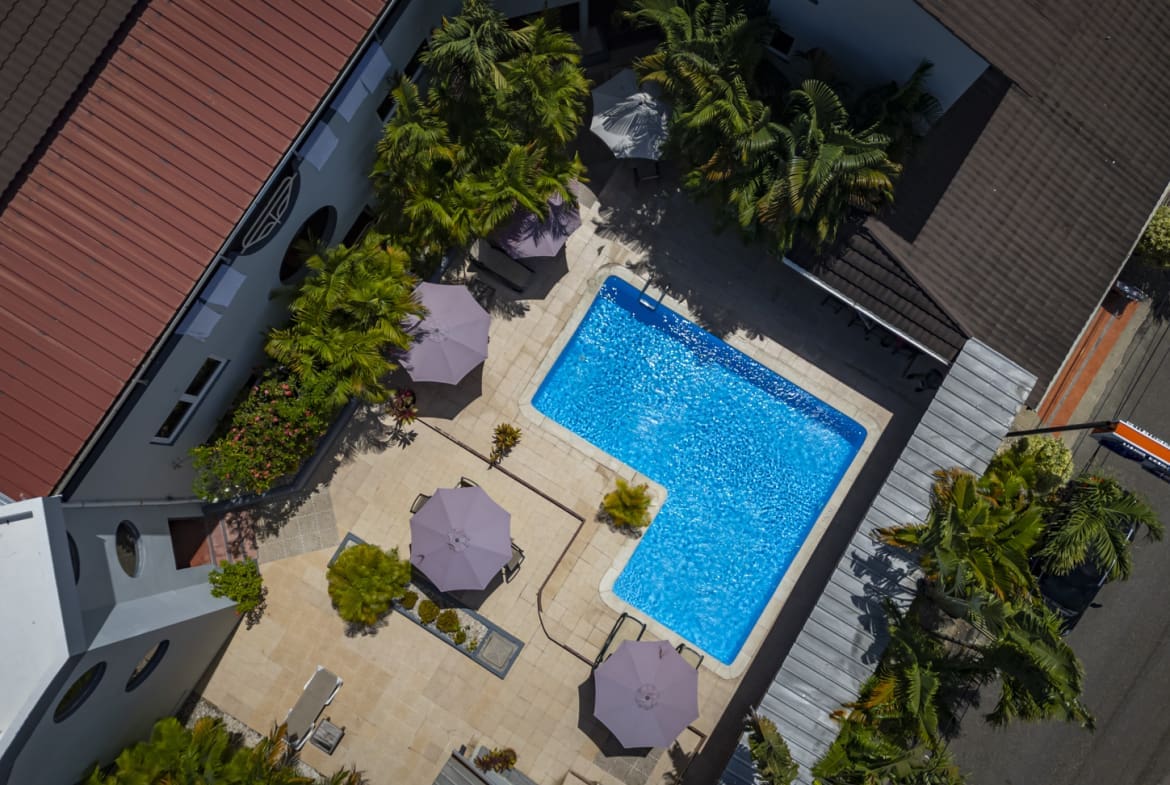 Aerial view of hotel Don Andres pool with lounge chairs and umbrellas, surrounded by palm trees