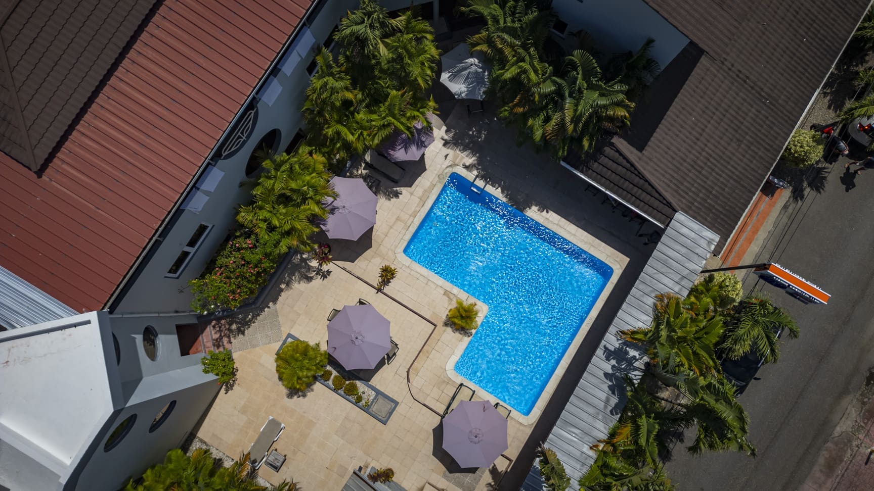 Aerial view of hotel Don Andres pool with lounge chairs and umbrellas, surrounded by palm trees