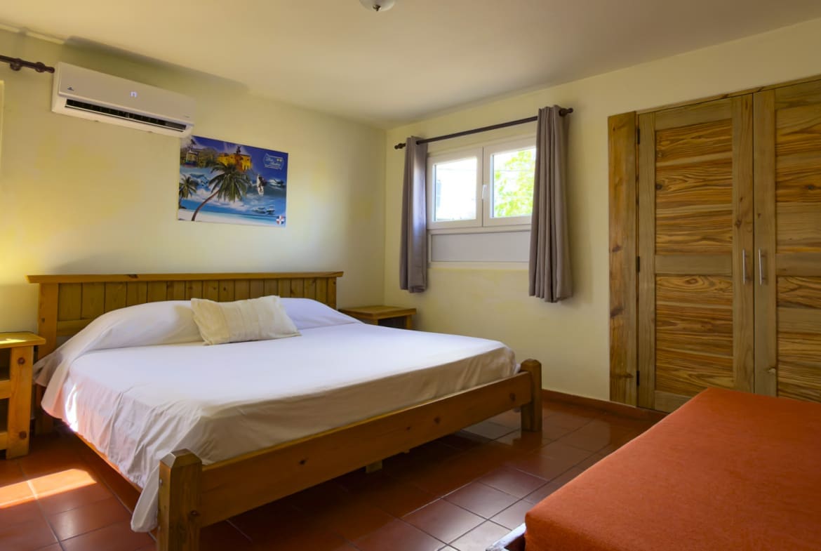 Cozy bedroom in Don Andrs with a king-size bed, wooden furniture, and tropical art.