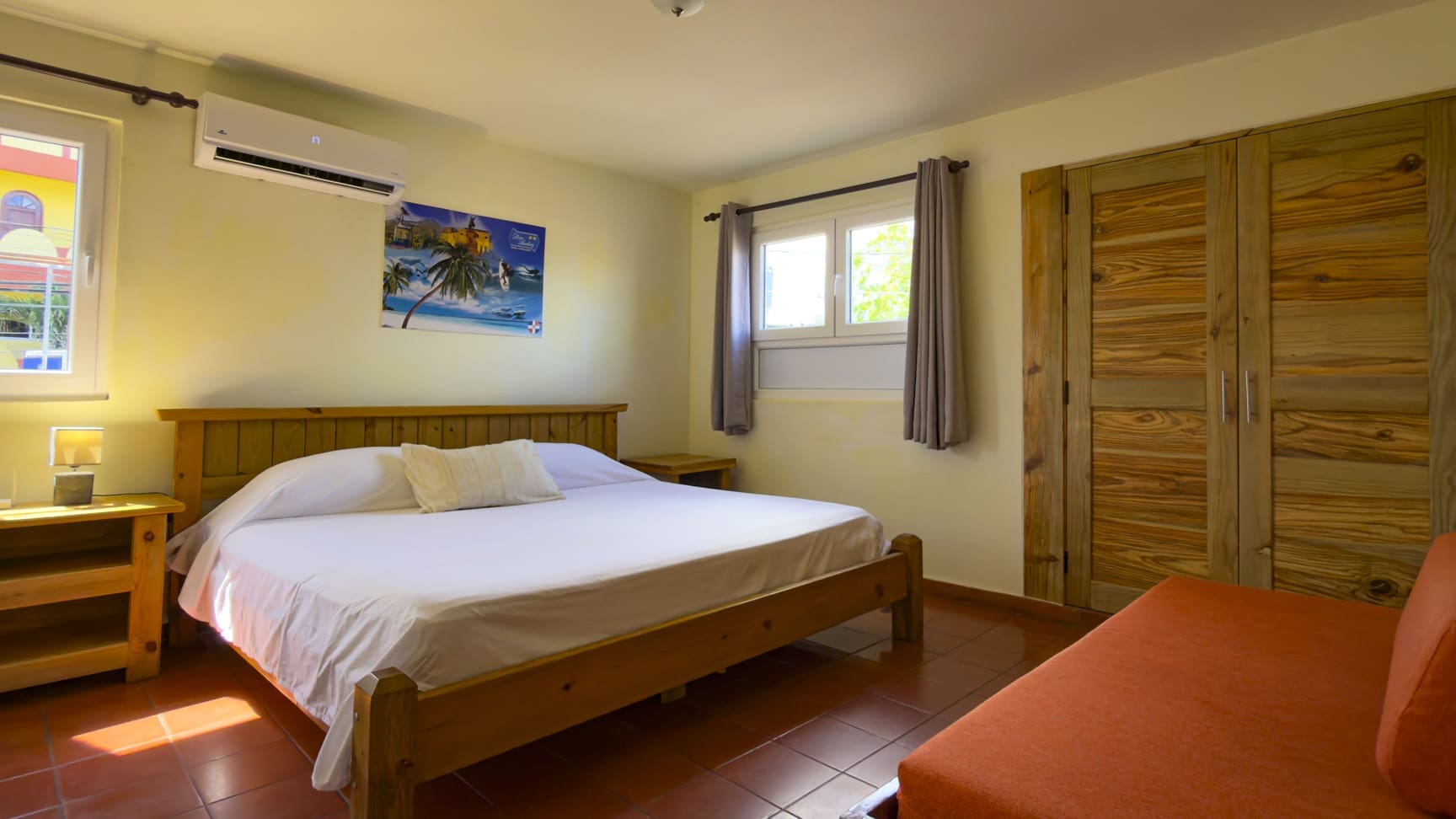 Cozy bedroom in Don Andrs with a king-size bed, wooden furniture, and tropical art.