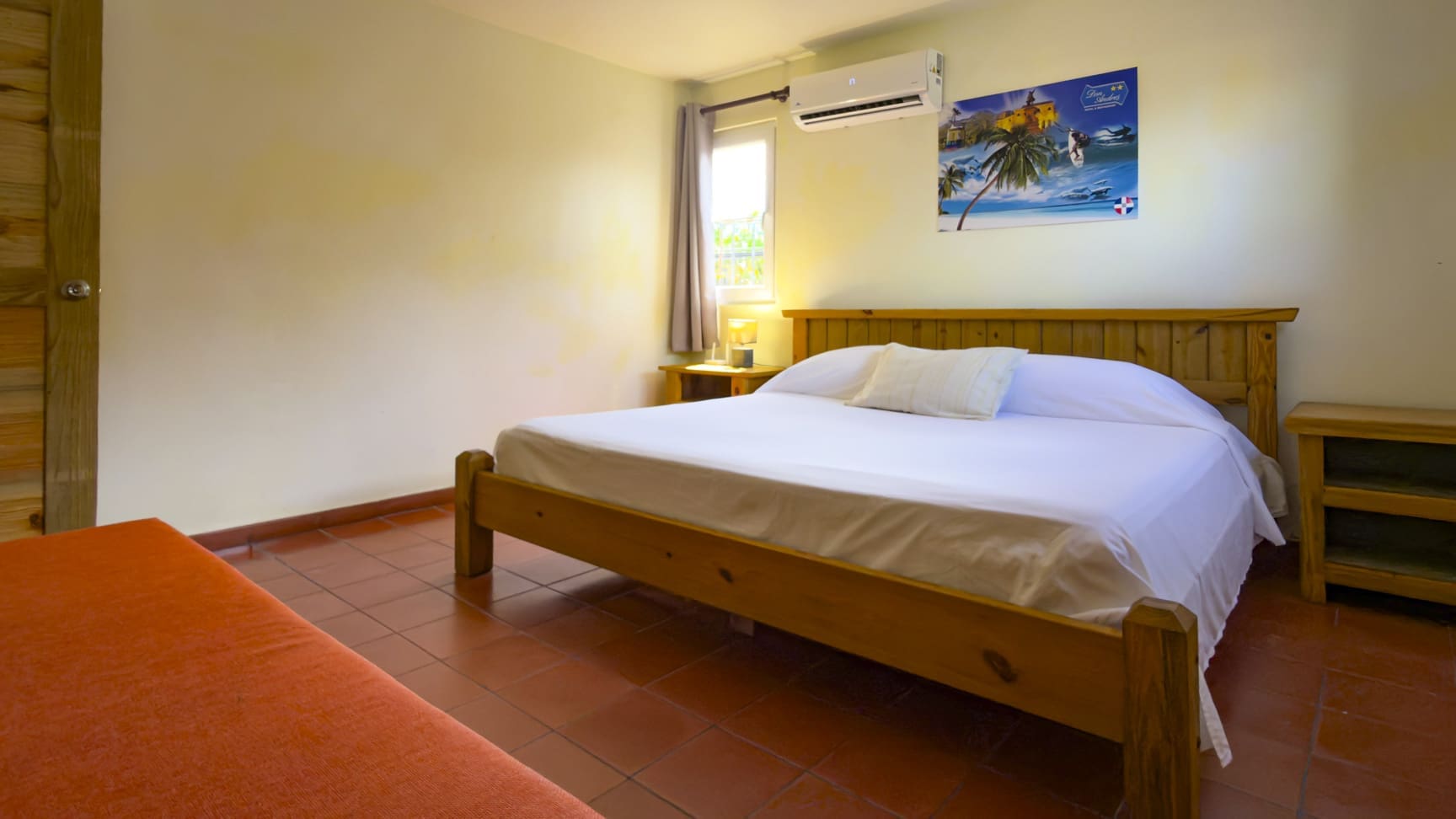 Wooden bed with white sheets in a cozy bedroom with red tiles