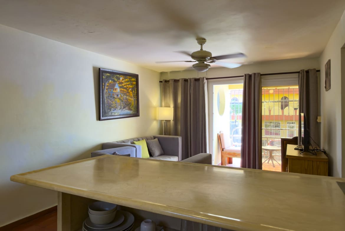 Bright living room with sofa, ceiling fan, and balcony view.