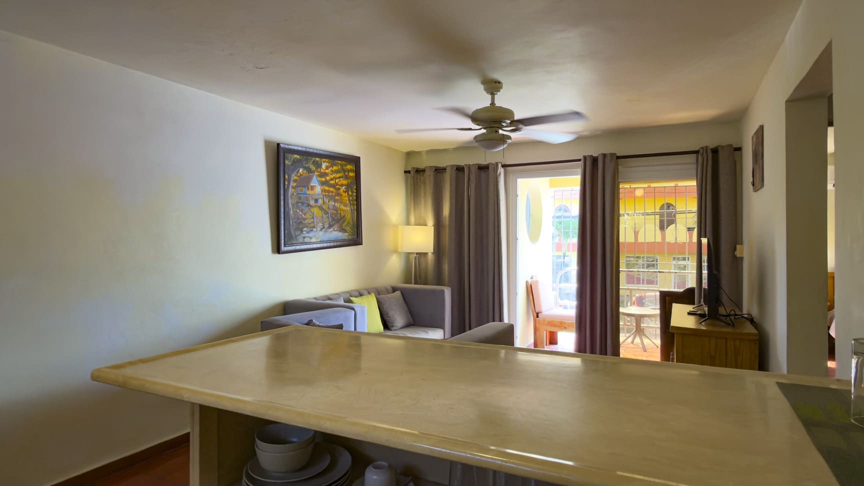 Bright living room with sofa, ceiling fan, and balcony view.