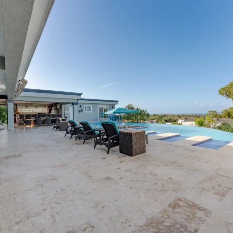 buyDRproperty Luxury infinity pool with lounge chairs and ocean view from patio Sosua Real Estate
