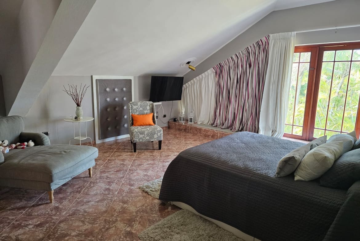 buyDRproperty Cozy bedroom with vaulted ceiling, armchair, and large bed Sosua Real Estate