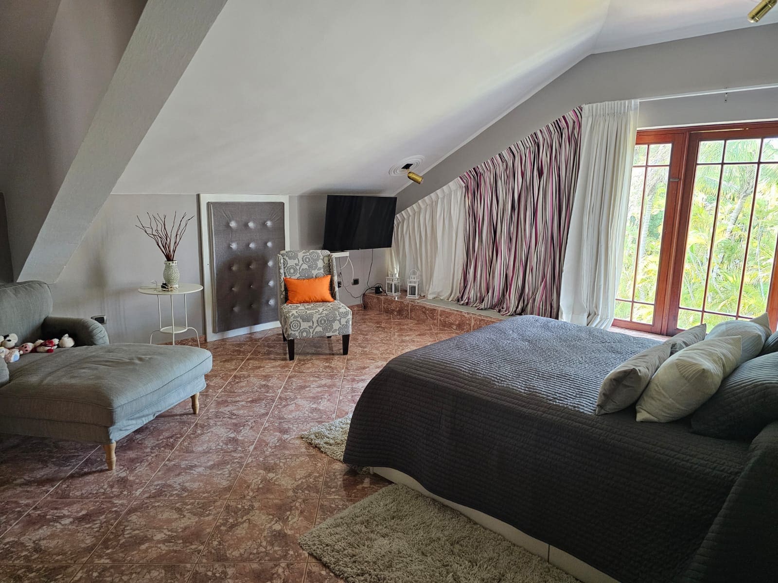 buyDRproperty Cozy bedroom with vaulted ceiling, armchair, and large bed Sosua Real Estate