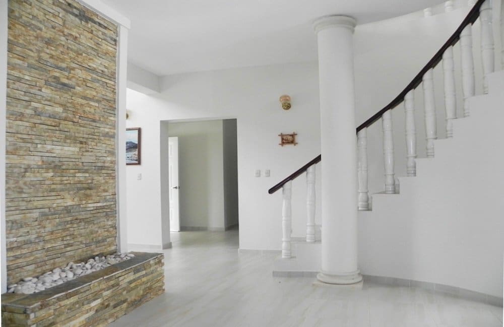 buyDRproperty Modern interior with a stone accent wall, white staircase, and column. Sosua Real Estate