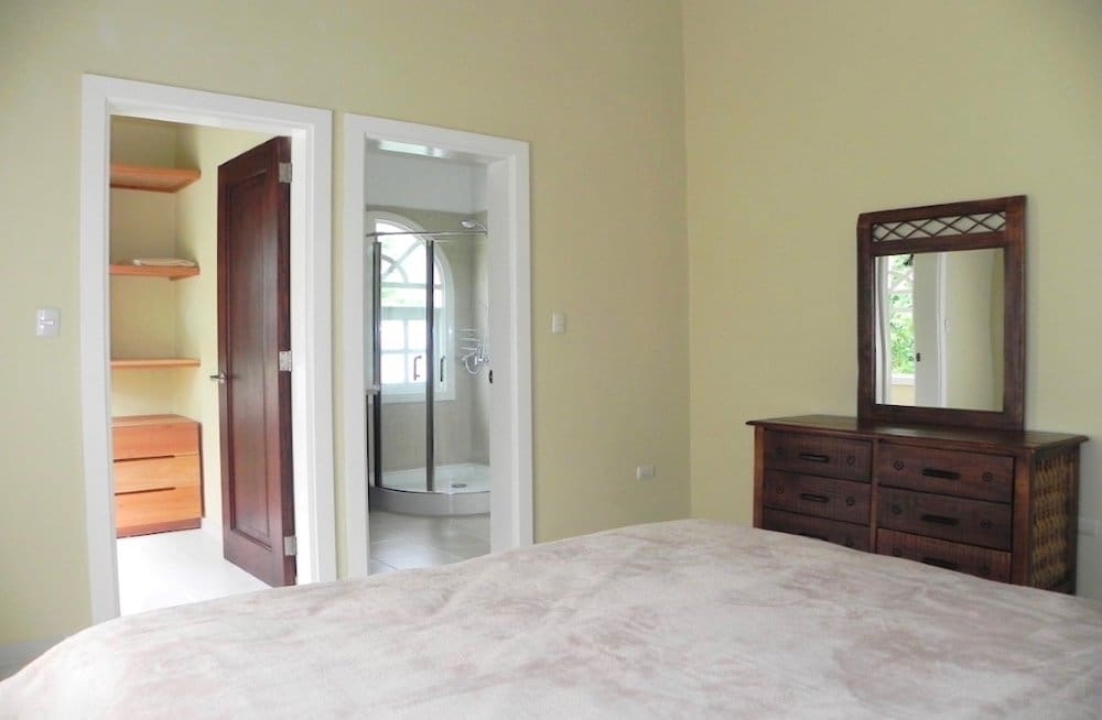 buyDRproperty Bedroom with walk-in closet and ensuite bathroom, featuring a dresser and mirror. Sosua Real Estate