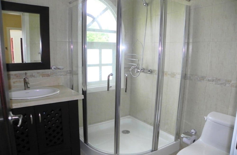 buyDRproperty Modern bathroom with a corner shower stall, vanity, and toilet. Sosua Real Estate