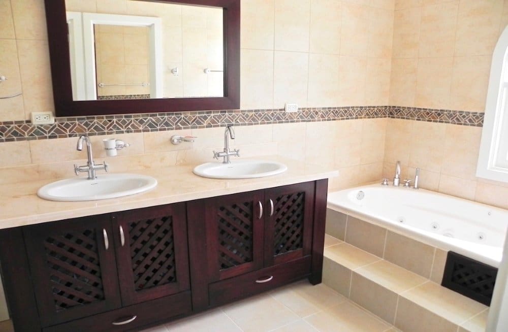 buyDRproperty Bathroom with double sinks, wooden cabinets, and a large bathtub Sosua Real Estate