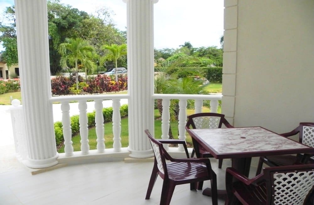 buyDRproperty White balcony with marble table and chairs, overlooking tropical garden Sosua Real Estate