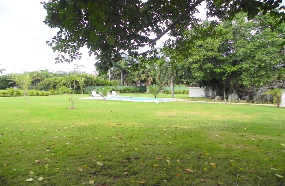 buyDRproperty Lush green lawn with a swimming pool and palm trees in a tropical setting. Sosua Real Estate