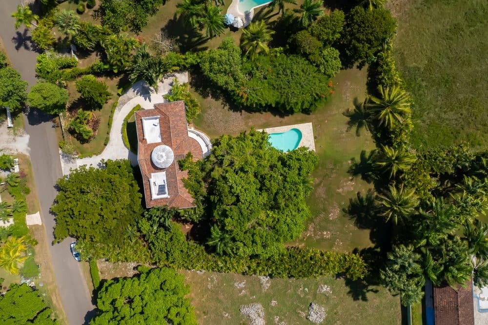 buyDRproperty Aerial view of a luxury villa with a pool surrounded by lush tropical greenery. Sosua Real Estate
