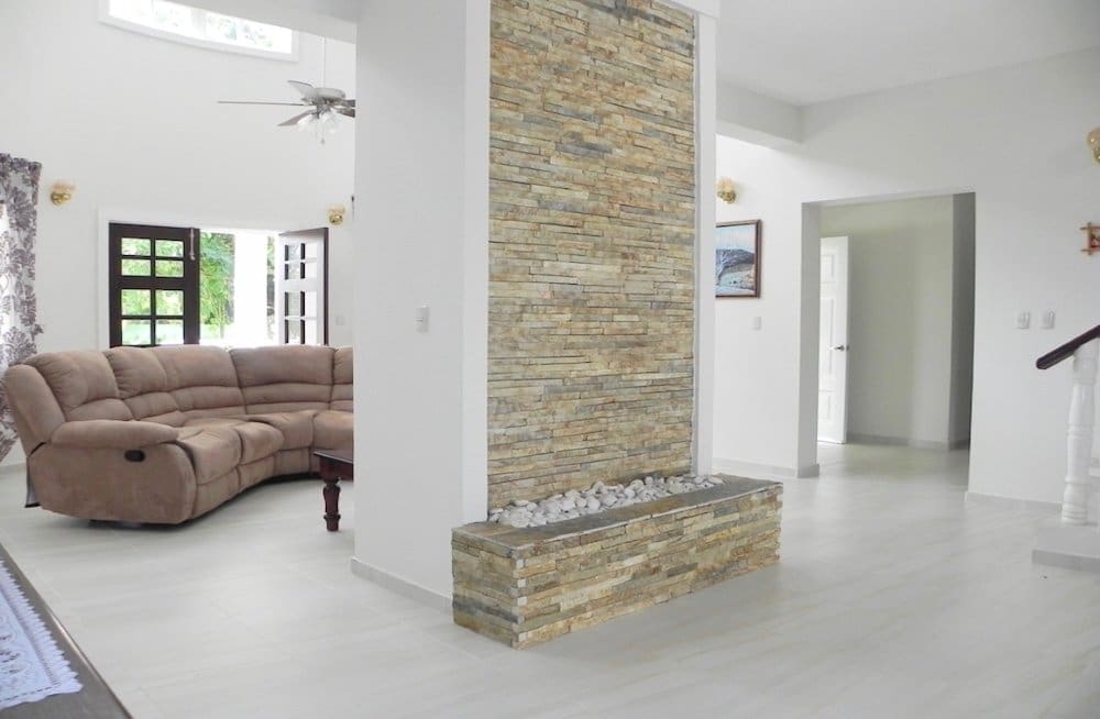 buyDRproperty Spacious living room with large sectional sofa and stacked stone accent wall Sosua Real Estate