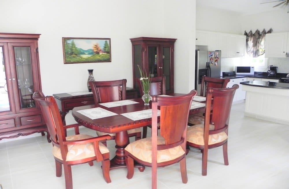 buyDRproperty Elegant mahogany dining set with table, chairs, and hutch in a bright dining room. Sosua Real Estate
