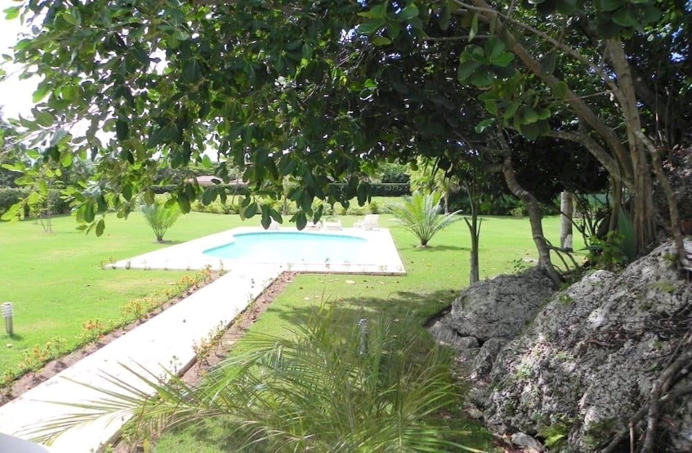 buyDRproperty Tropical villa with pool, palm trees, and lush green lawn. Sosua Real Estate