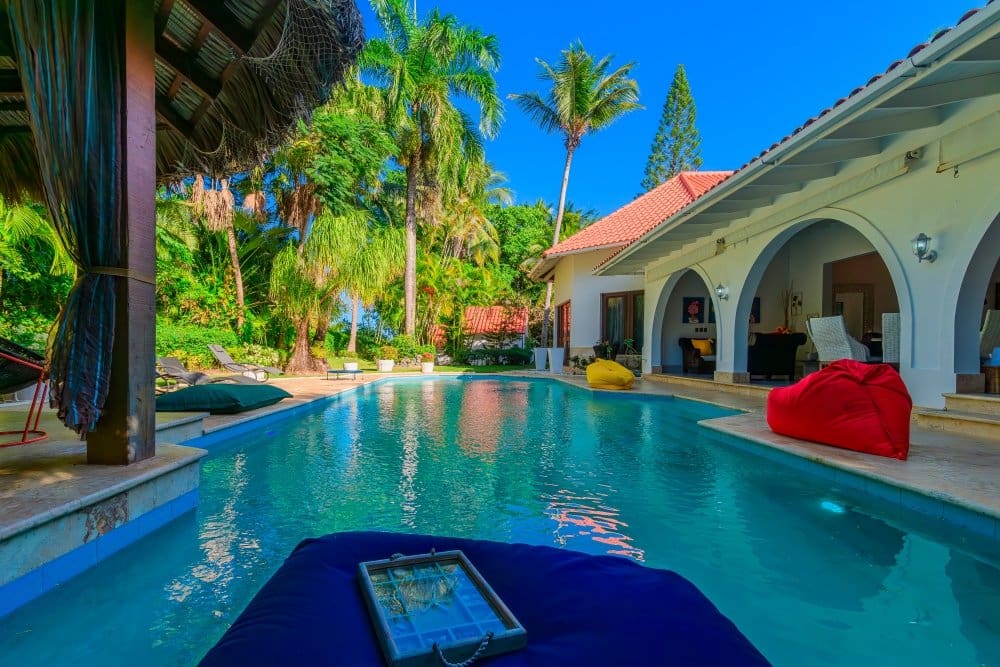 buyDRproperty Luxury villa with outdoor pool, lounge chairs, and tropical trees Sosua Real Estate