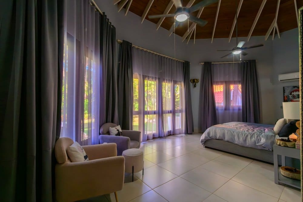 buyDRproperty Spacious bedroom with king-size bed, sitting area, and ceiling fans. Sosua Real Estate