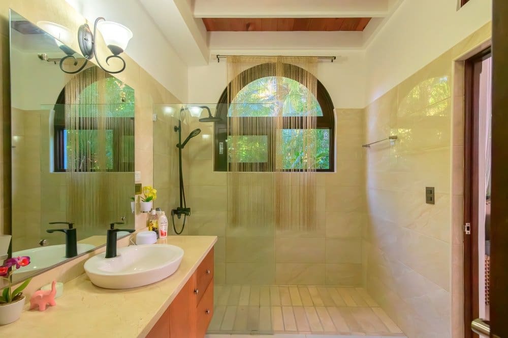 buyDRproperty Modern bathroom with arched window, walk-in shower, and vanity Sosua Real Estate