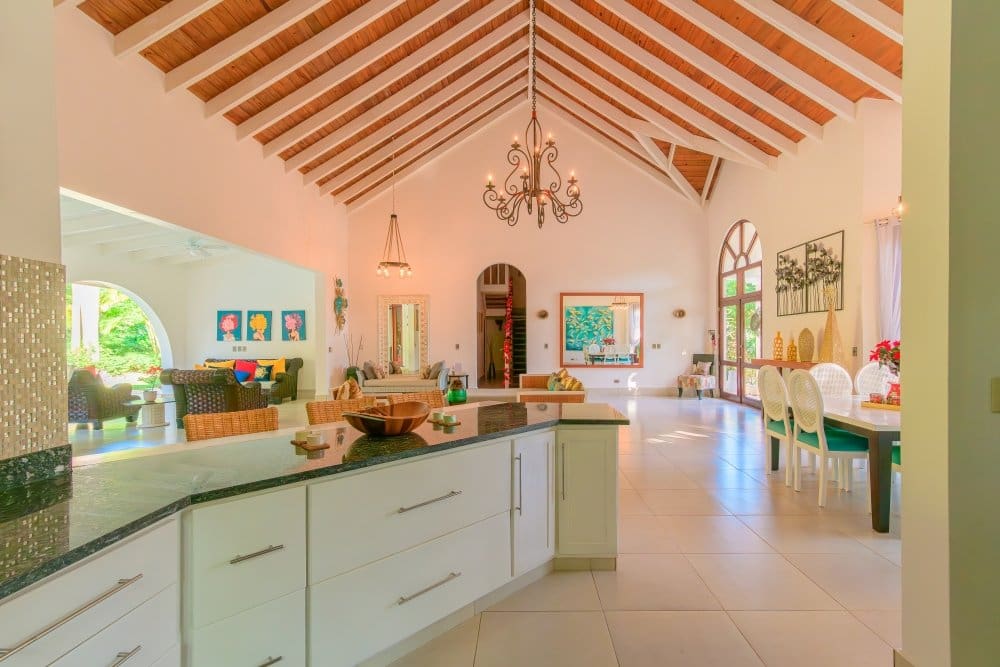 buyDRproperty Spacious open-plan living area with vaulted ceiling, modern kitchen island, and dining set Sosua Real Estate