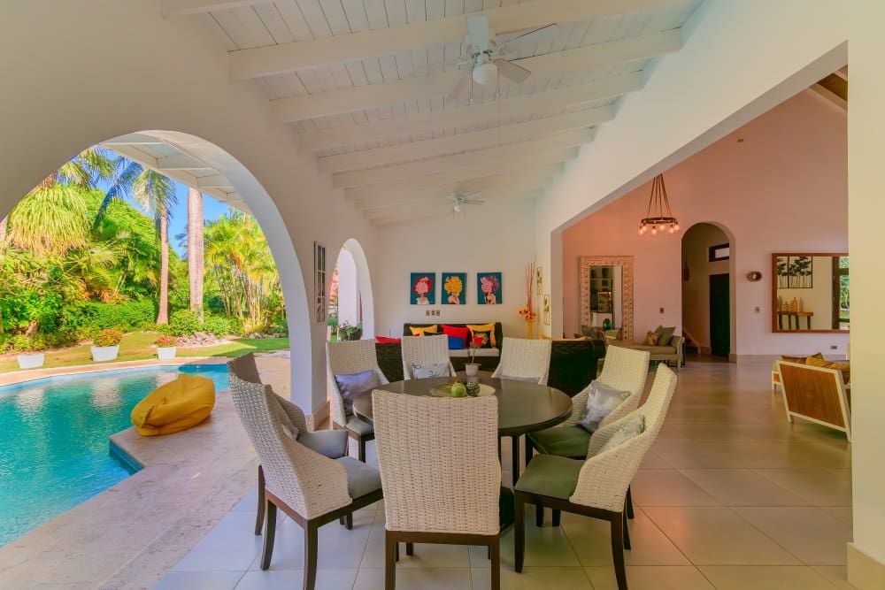 buyDRproperty Covered patio dining area with pool and tropical garden view Sosua Real Estate