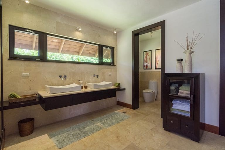 buyDRproperty Modern bathroom with double vessel sinks, natural stone, and a glass-door cabinet. Sosua Real Estate