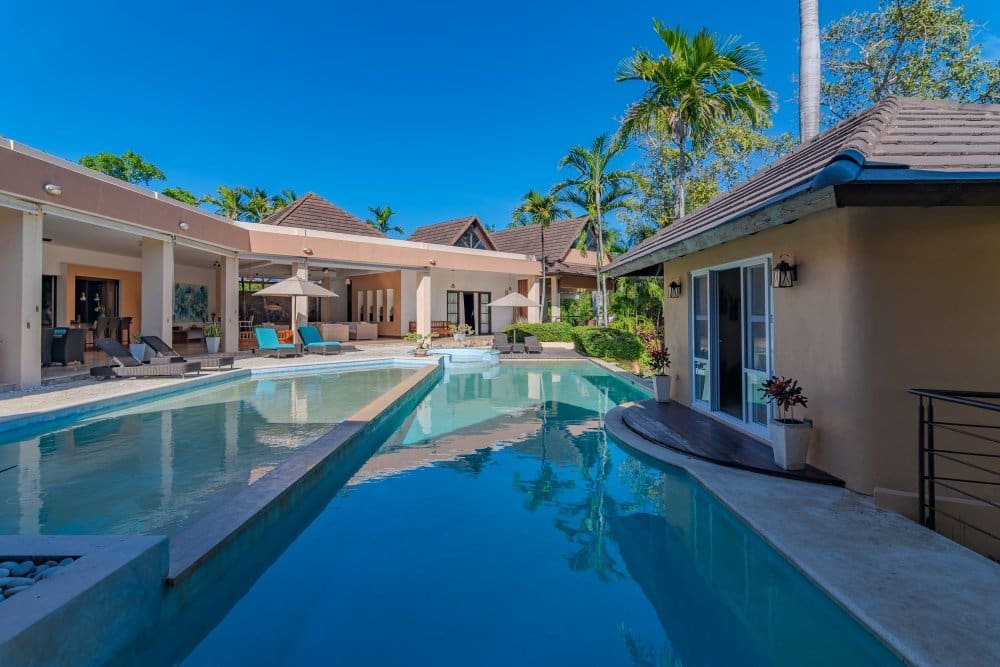buyDRproperty Luxury villa with pool, palm trees, and outdoor seating area. Sosua Real Estate