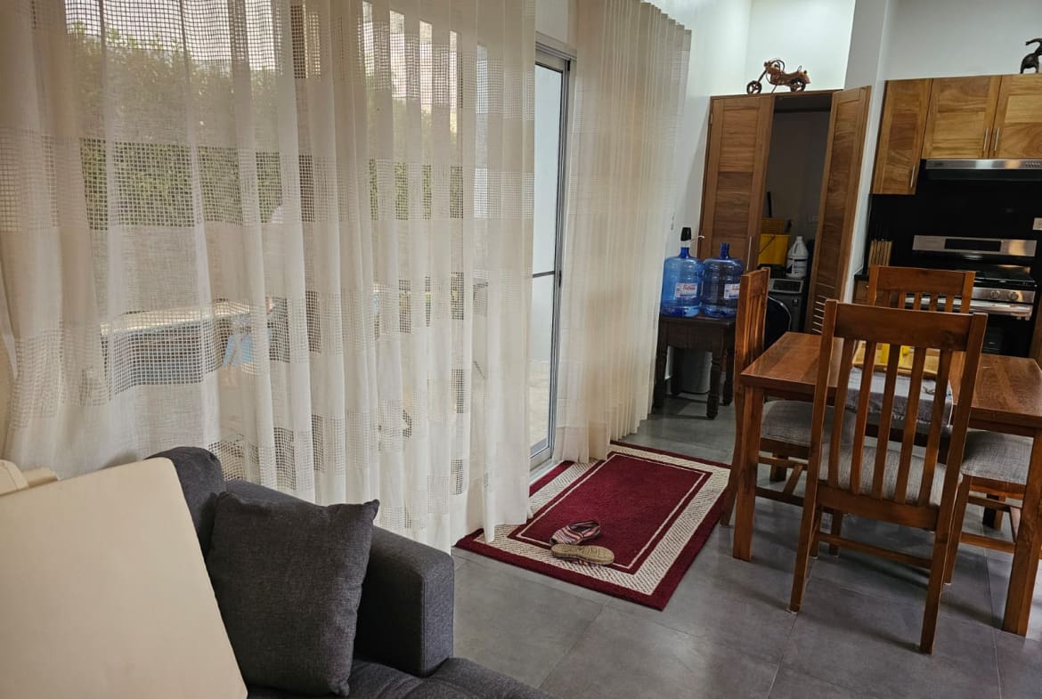 buyDRproperty Modern living room with sheer curtains, sofa, dining table, and kitchen cabinets Sosua Real Estate
