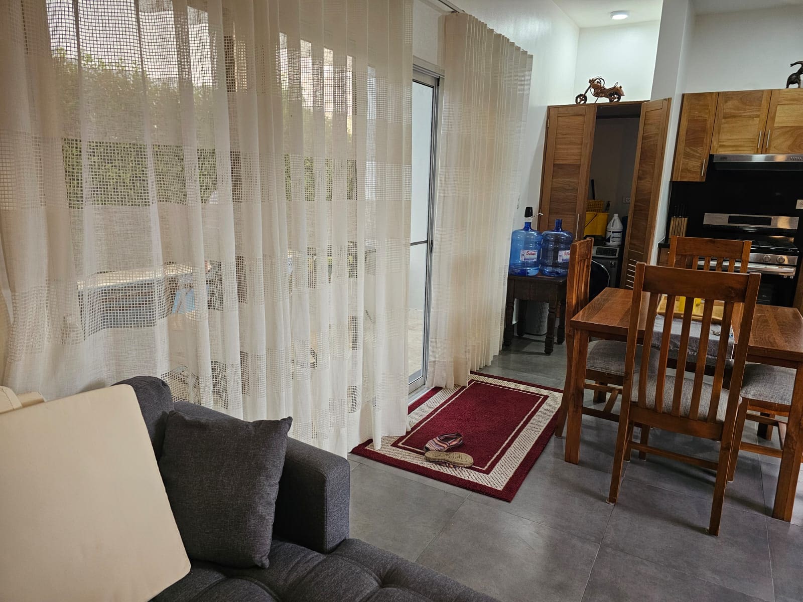 buyDRproperty Modern living room with sheer curtains, sofa, dining table, and kitchen cabinets Sosua Real Estate