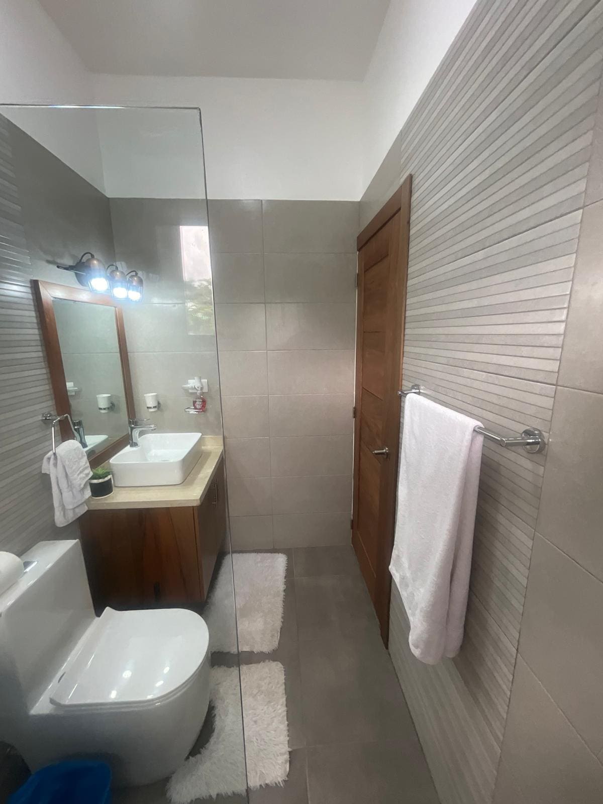 buyDRproperty Modern bathroom with a square sink, wooden vanity, and glass shower enclosure. Sosua Real Estate