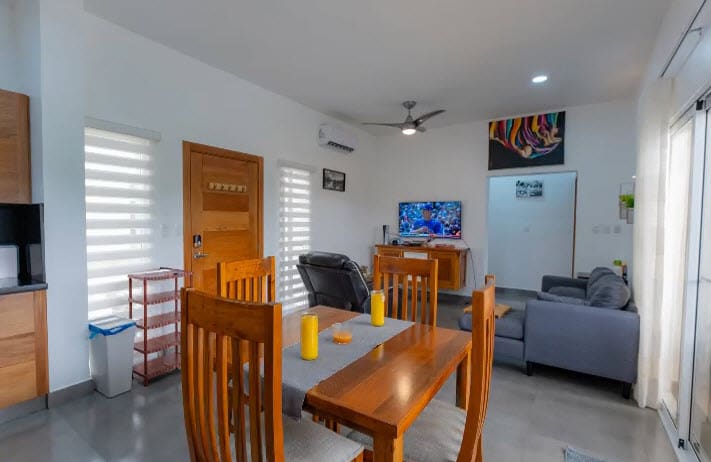 buyDRproperty Modern dining area with wooden table, chairs, and living room with TV. Sosua Real Estate