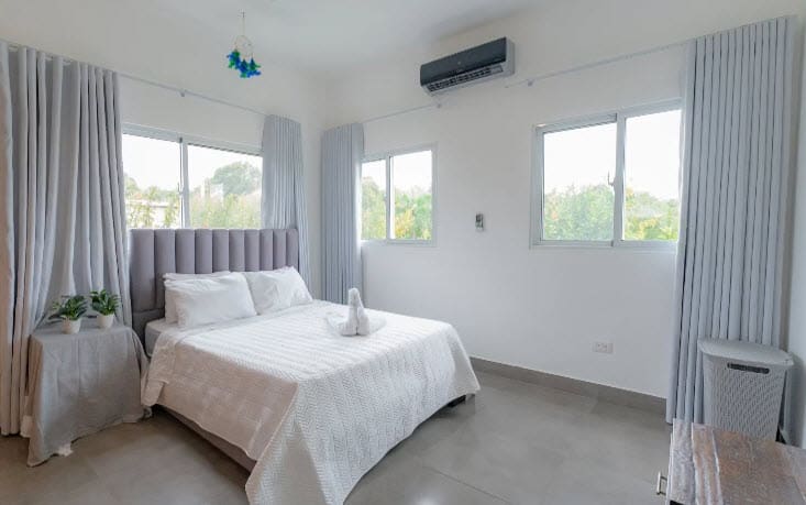 buyDRproperty Modern bedroom with a king-size bed, white linens, and large windows. Sosua Real Estate