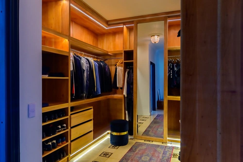 buyDRproperty Luxurious walk-in closet with custom wooden cabinetry, organized clothing, and ambient lighting. Sosua Real Estate
