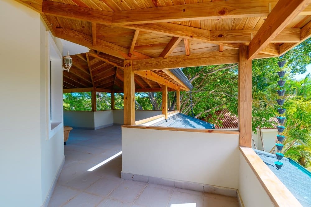 buyDRproperty Wooden covered balcony with tropical trees and chain rain gutter Sosua Real Estate