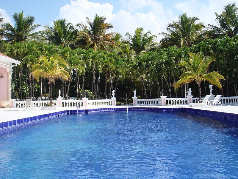 buyDRproperty Luxurious swimming pool with palm trees and white railings Sosua Real Estate