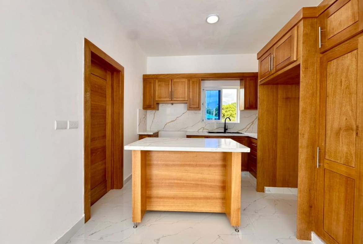 Modern wood kitchen with island, white marble countertops, and stainless steel sink.