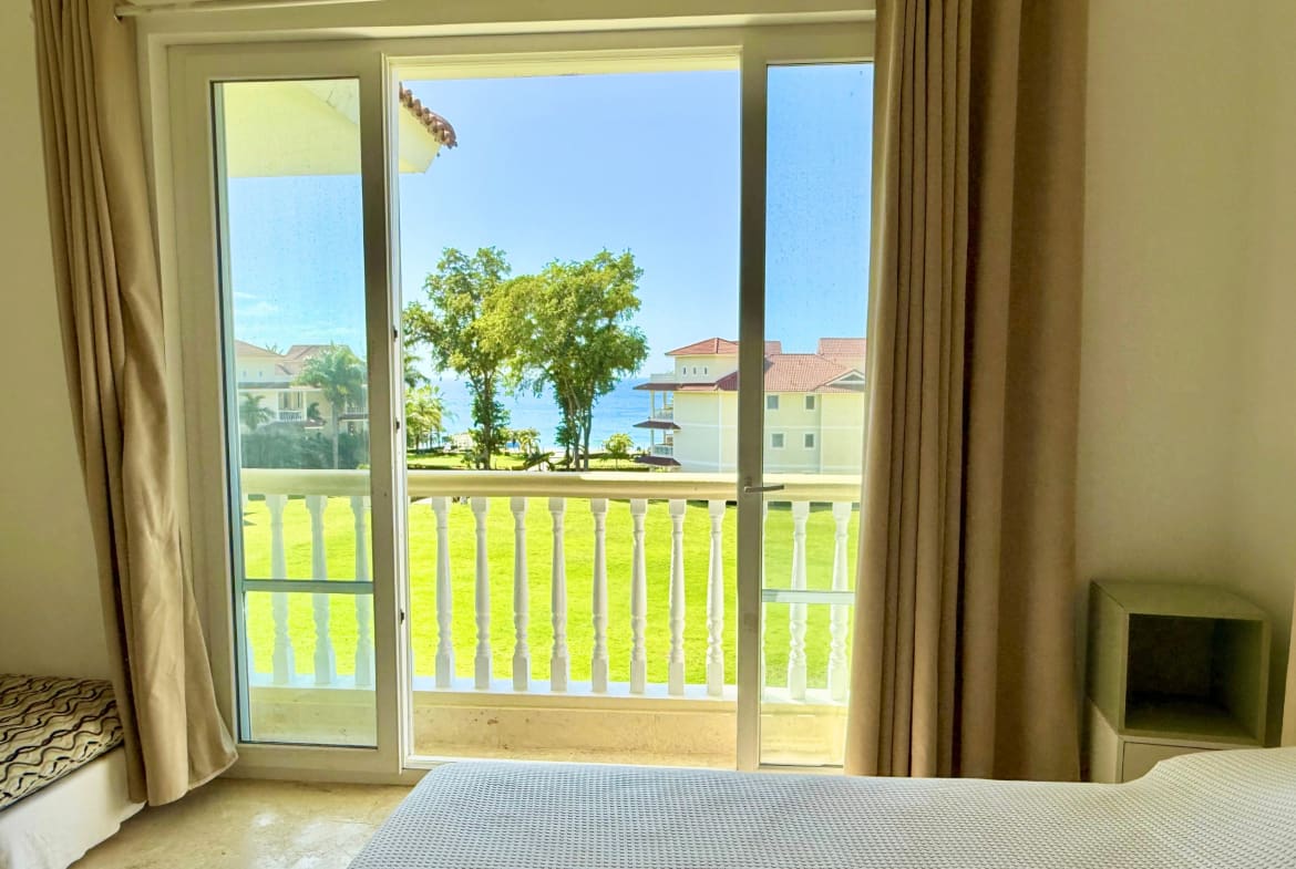View from bedroom of balcony overlooking green lawn and ocean