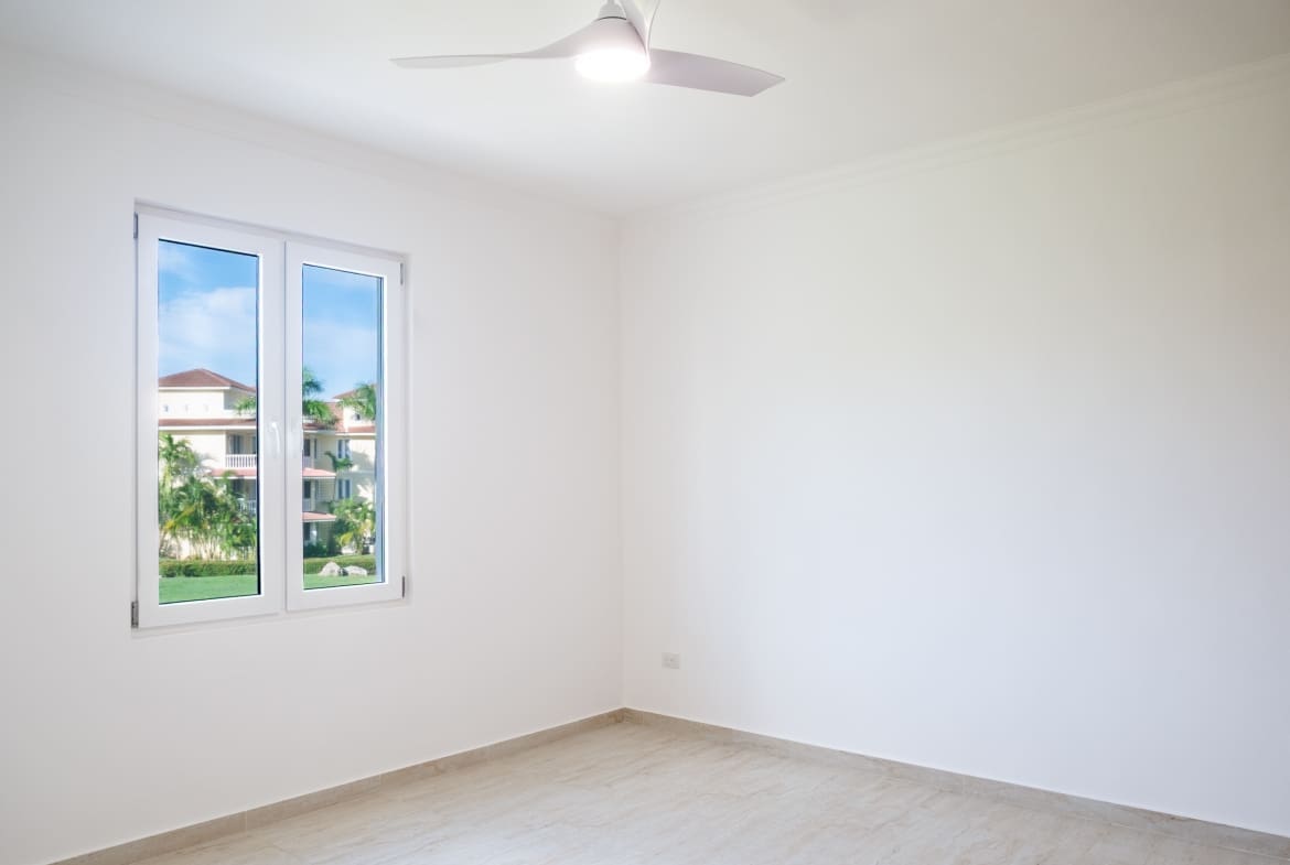 Bright bedroom with ceiling fan, large window and tropical garden views at Hispaniola Beach condo in Sosua