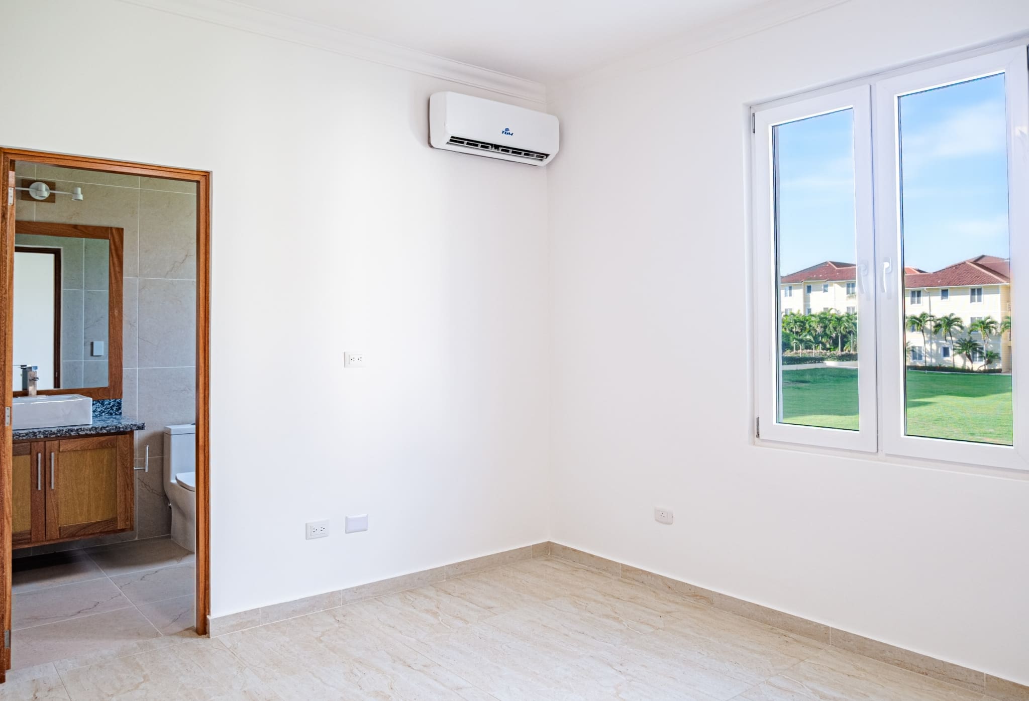 Bright bedroom with air conditioning, private bathroom and tropical garden views at Hispaniola Beach condo in Sosua